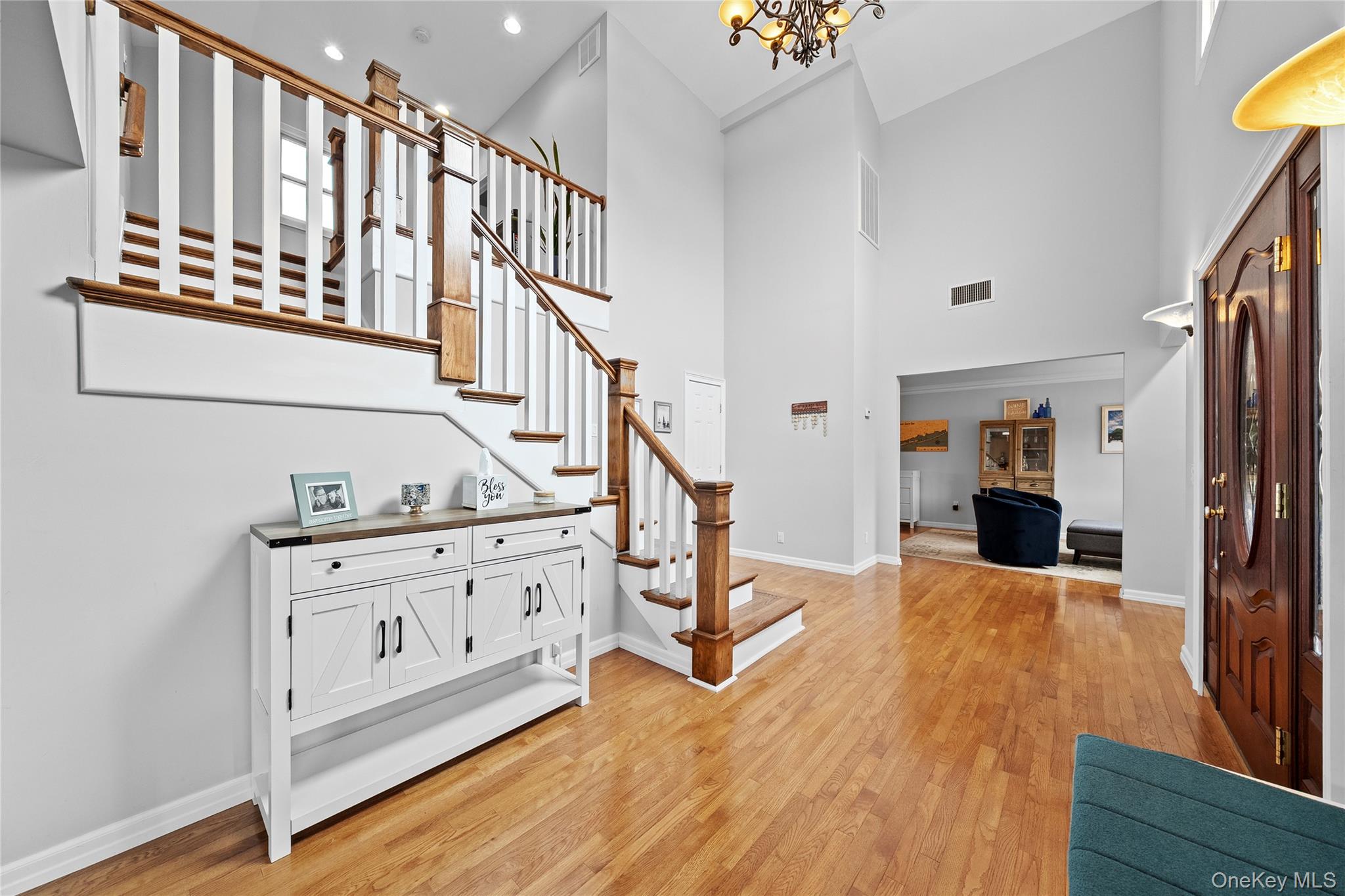 625 Edgewater Road Oakdale, NY 11769 - Photo 20 of 49 Entrance foyer with light wood finished floors, stairs, a towering ceiling, and a chandelier