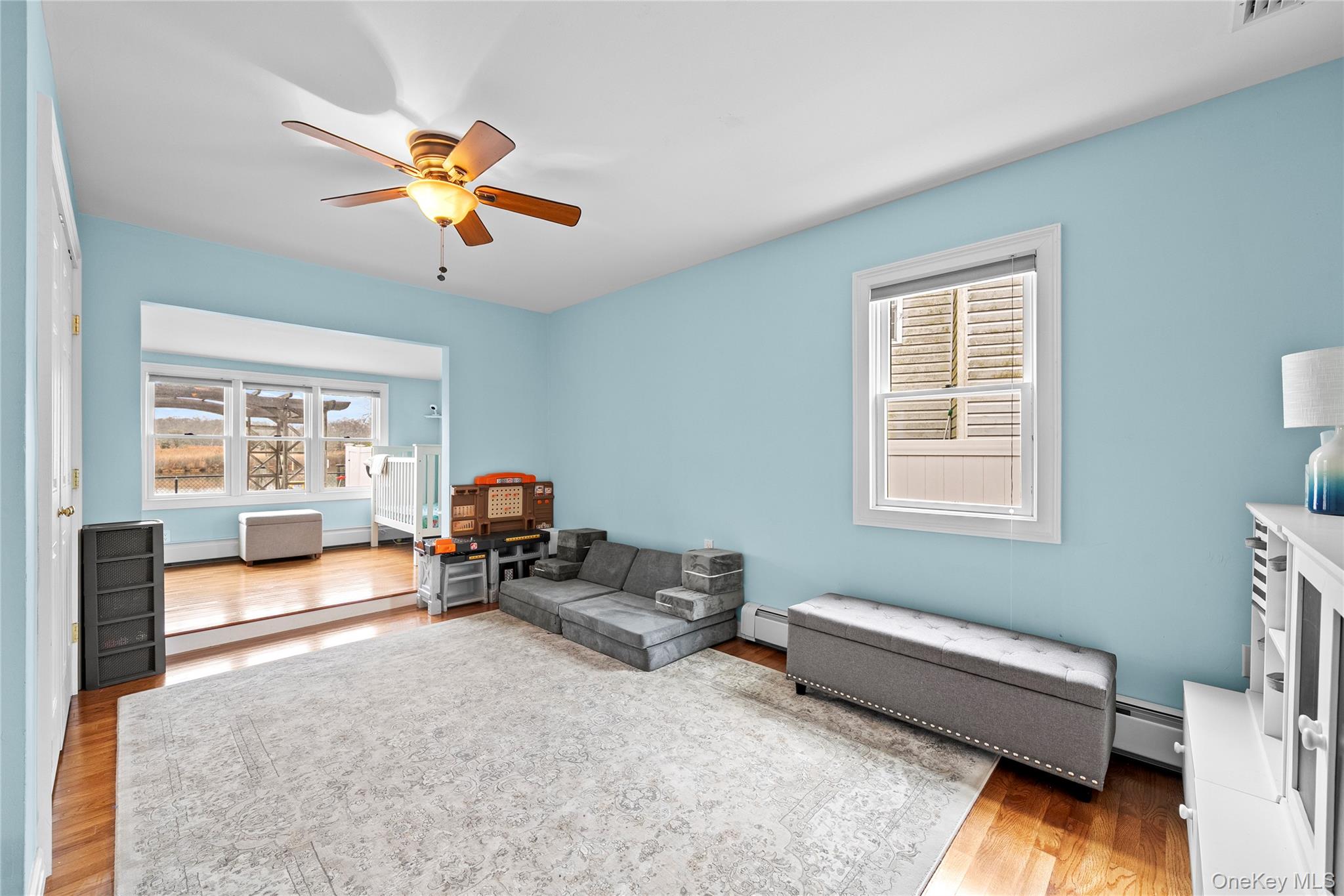 625 Edgewater Road Oakdale, NY 11769 - Photo 26 of 49 Living room featuring baseboard heating, light wood finished floors, and ceiling fan