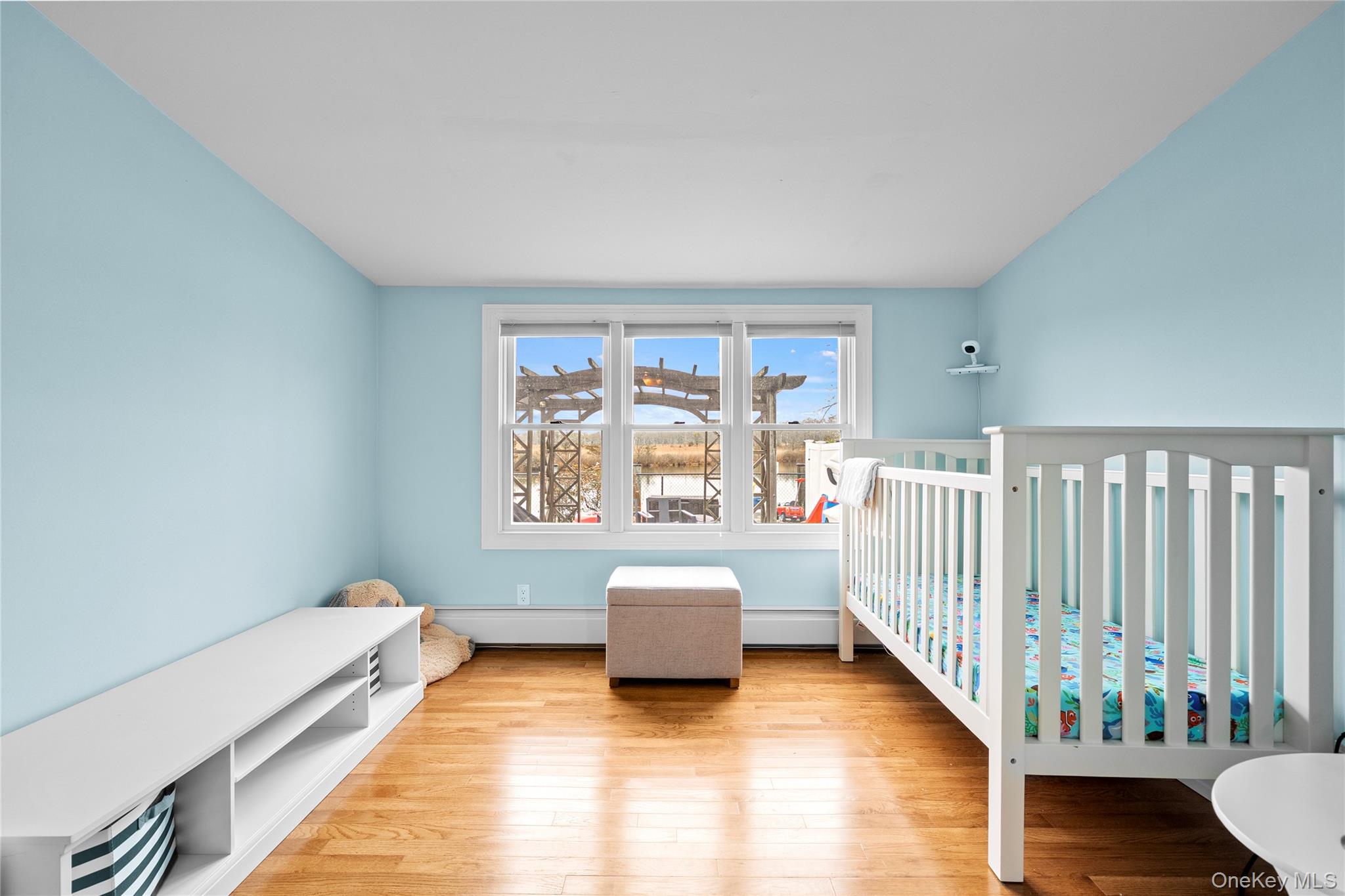 625 Edgewater Road Oakdale, NY 11769 - Photo 27 of 49 Bedroom with wood-type flooring, a crib, and a baseboard heating unit