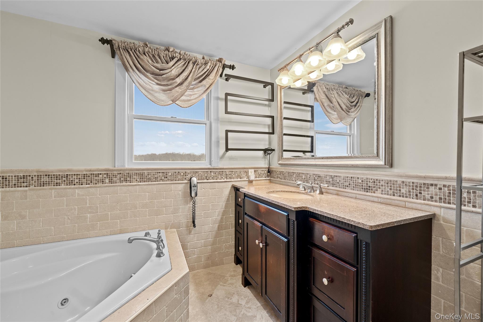625 Edgewater Road Oakdale, NY 11769 - Photo 34 of 49 Full bath featuring wainscoting, vanity, a tub with jets, healthy amount of natural light, and tile walls