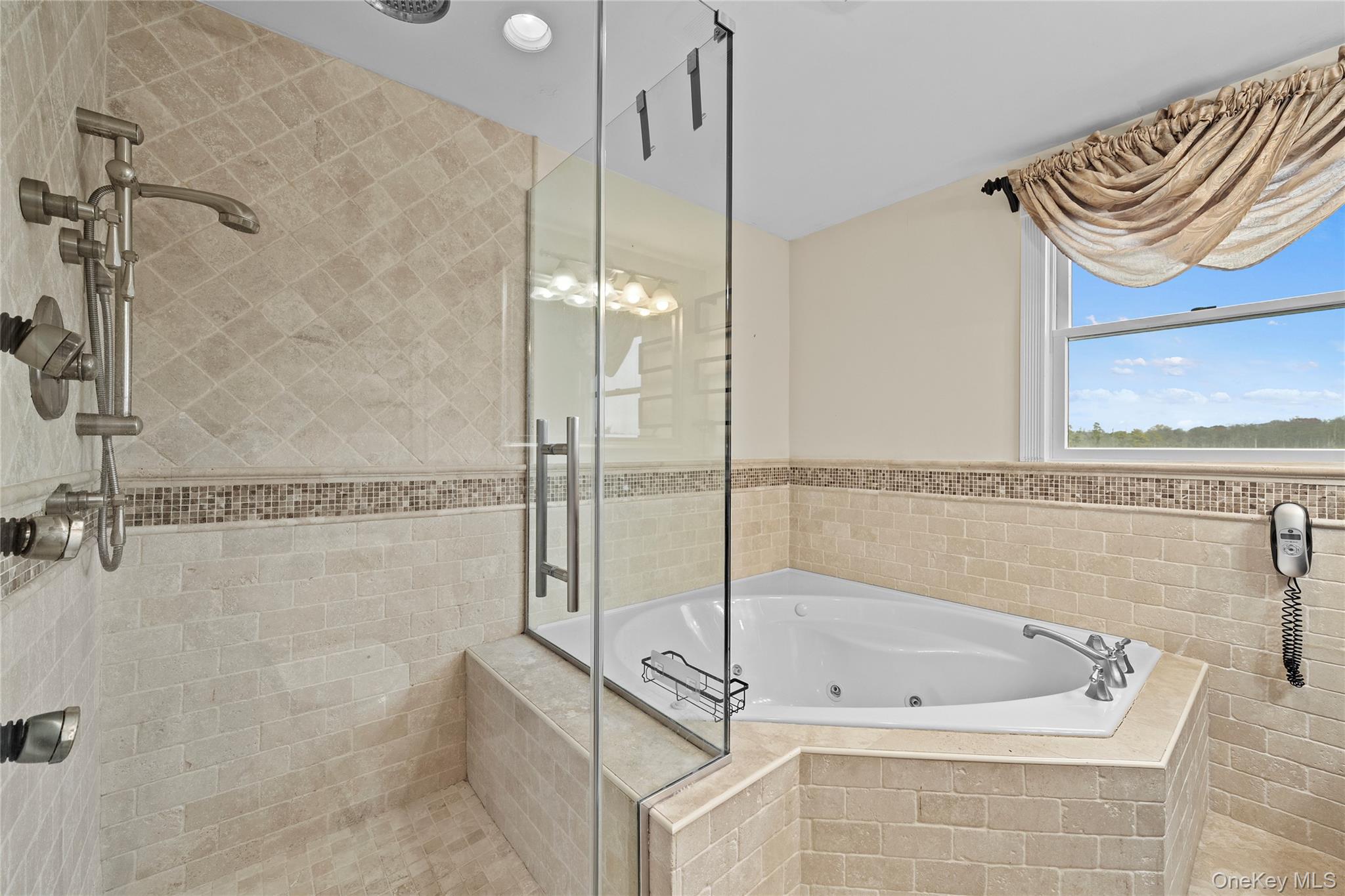 625 Edgewater Road Oakdale, NY 11769 - Photo 36 of 49 Full bath with a tub with jets, a wainscoted wall, a stall shower, and tile walls