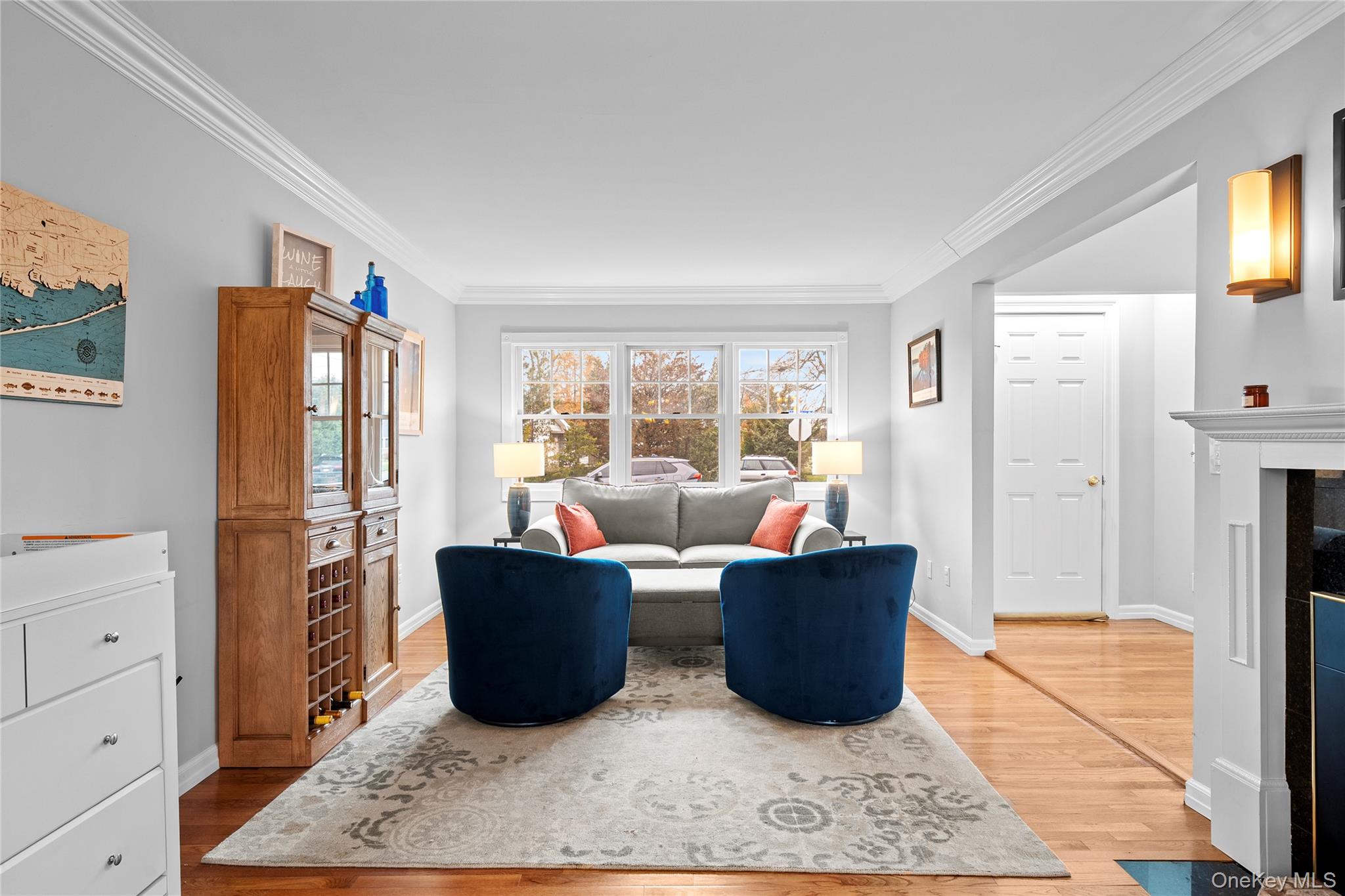 625 Edgewater Road Oakdale, NY 11769 - Photo 8 of 49 Living area featuring crown molding, light wood-type flooring, and a fireplace with flush hearth