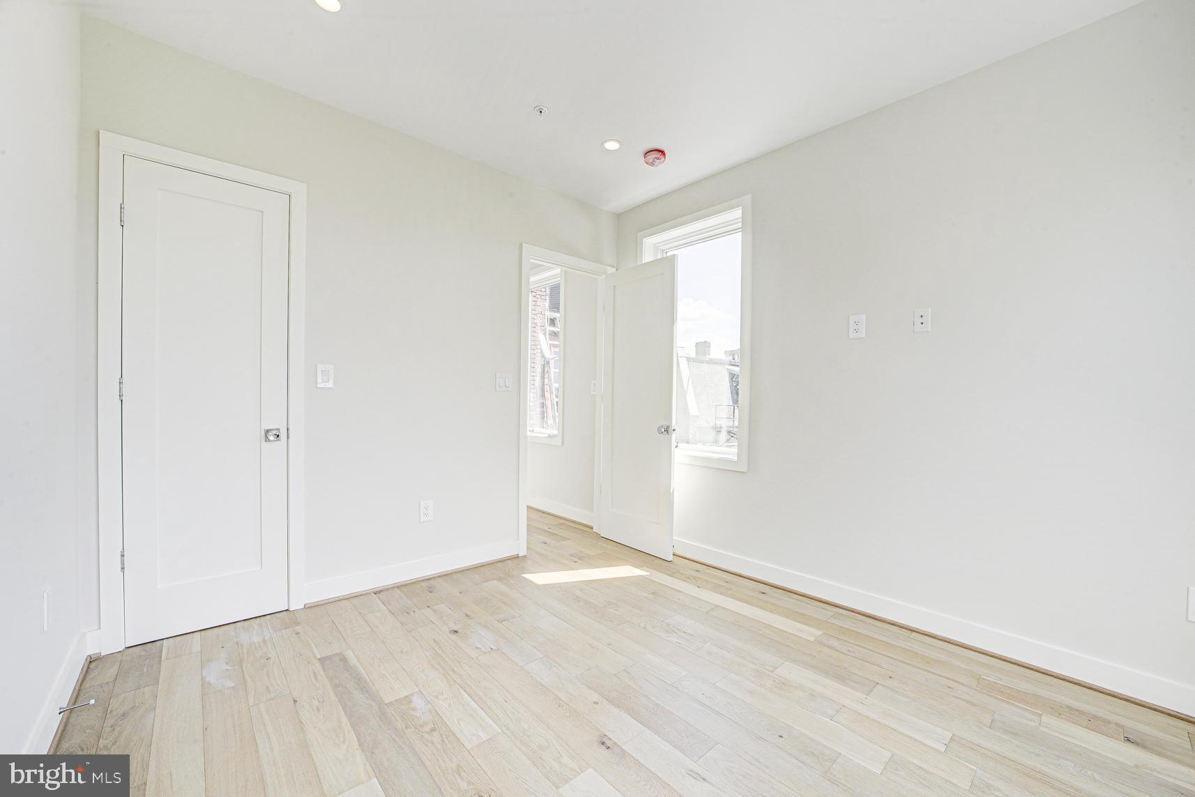 3118 Mt Pleasant Street Northwest, Unit 3 Washington, DC 20010 - Photo 11 of 16 an empty room with wooden floor and windows