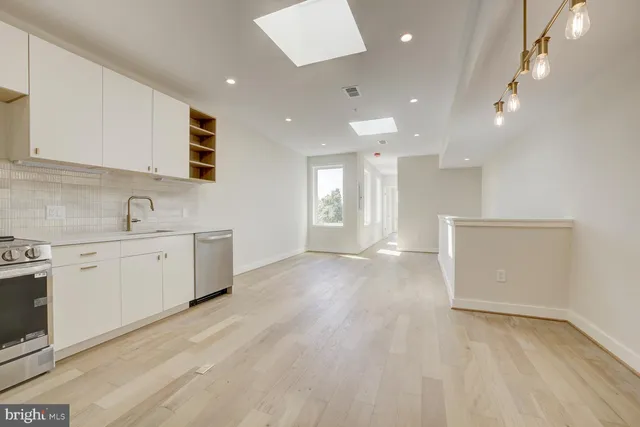 a view of a kitchen with a sink and dishwasher a stove top oven with wooden floor