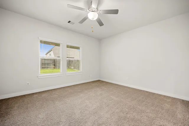 an empty room with chandelier fan and windows