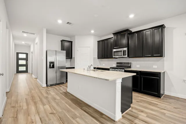 a kitchen with stainless steel appliances granite countertop a stove top oven a sink and a refrigerator