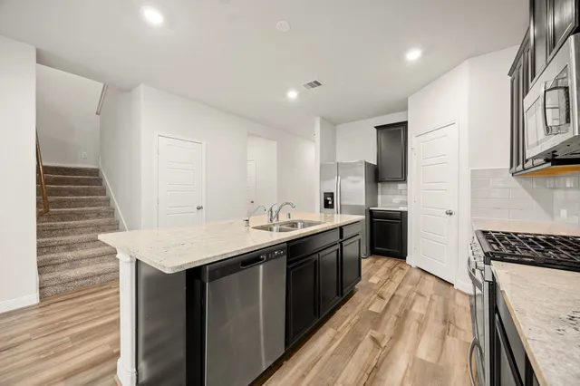 a kitchen with stainless steel appliances granite countertop a sink stove and refrigerator