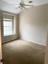 an empty room with windows and fan