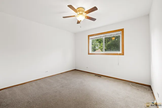 an empty room with a window and a ceiling fan