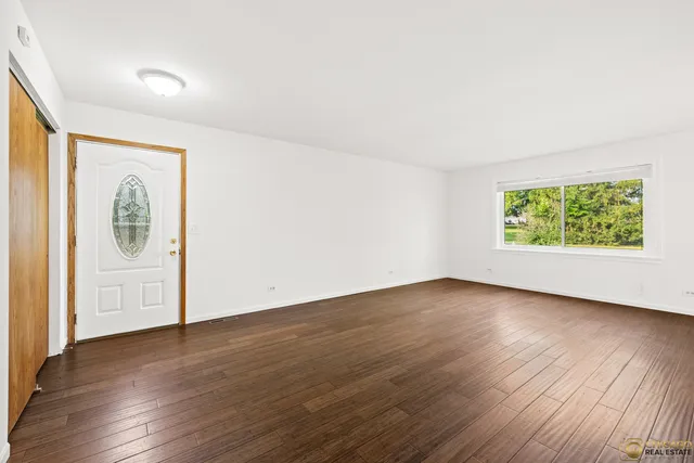 an empty room with wooden floor and window