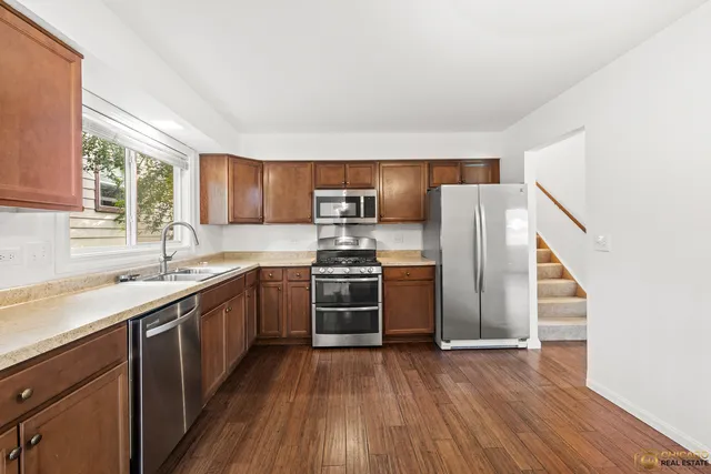 a kitchen with stainless steel appliances granite countertop a refrigerator a sink dishwasher a stove with wooden floors and cabinets