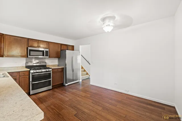 a kitchen with granite countertop a refrigerator and a stove top oven