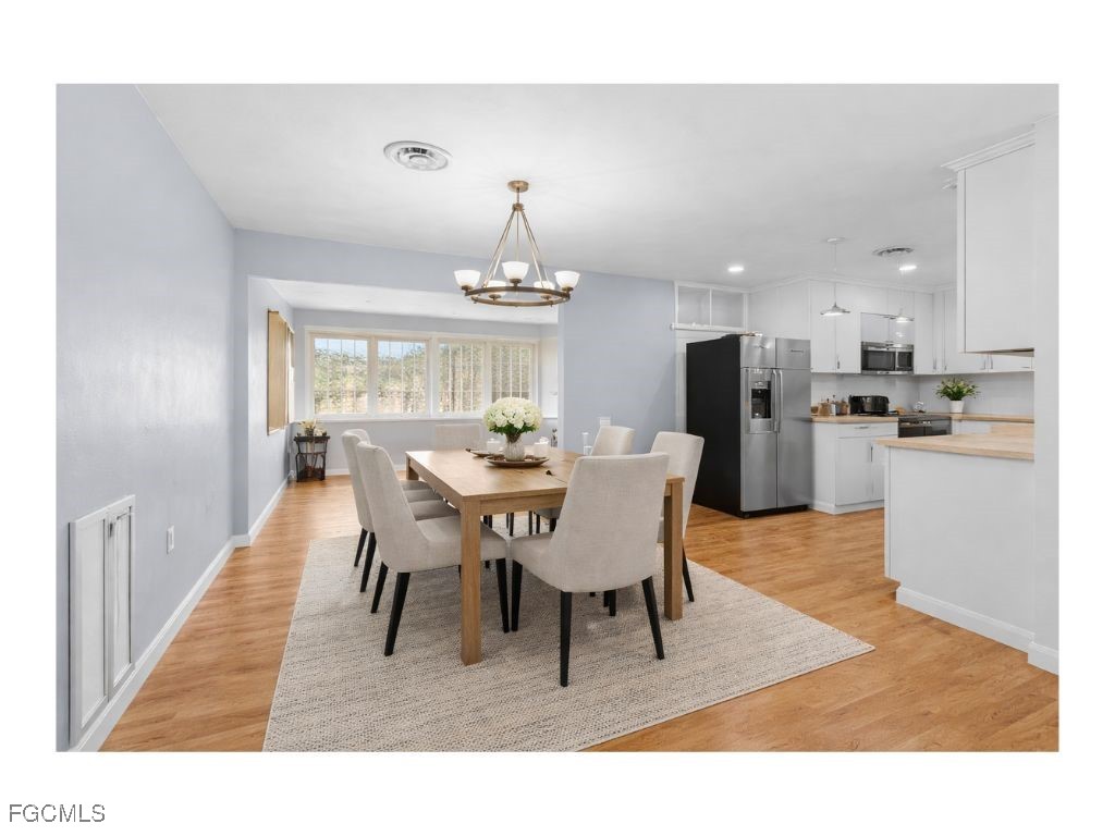 a dining room with wooden floor a chandelier a wooden table and chairs