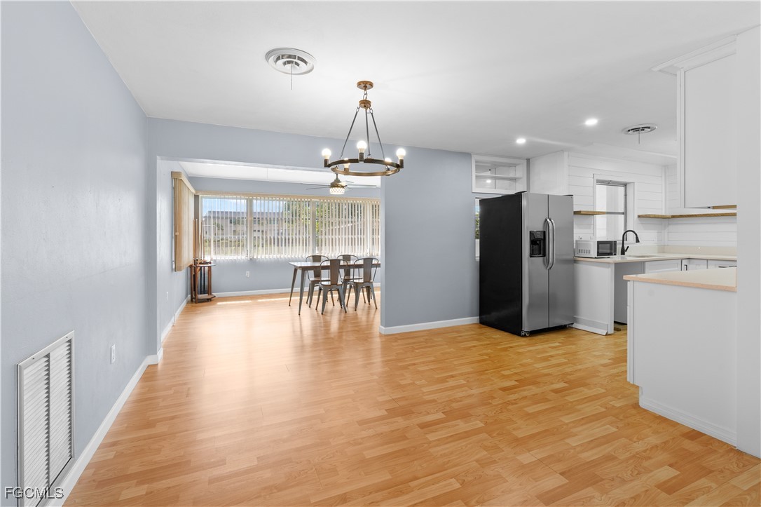 1450 Charles Road Fort Myers, FL 33919 - Photo 7 of 23 a kitchen with stainless steel appliances kitchen island granite countertop a refrigerator a stove a dining table and chairs with wooden floor