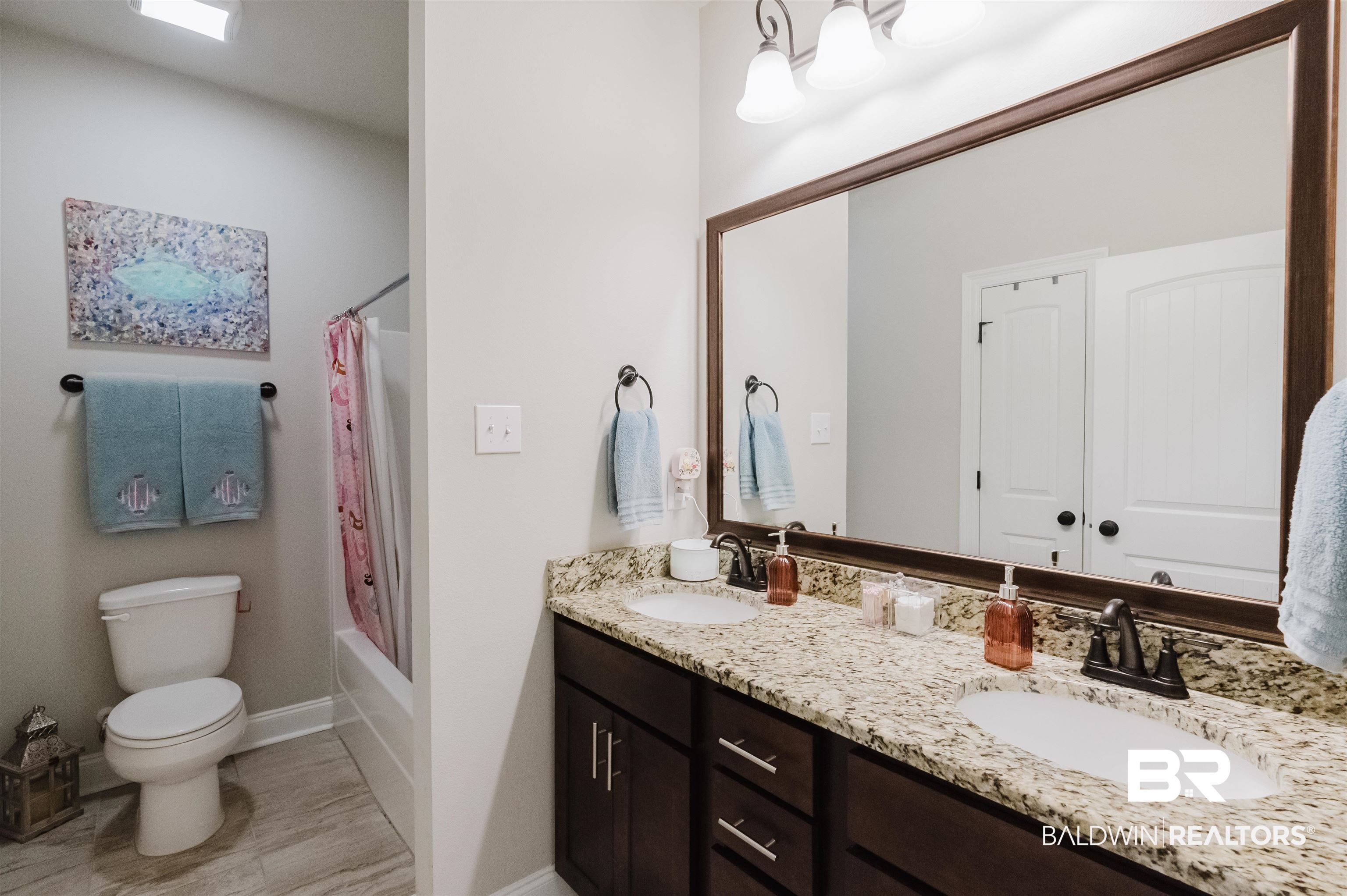 12128 Red Barn Road Fairhope, AL 36532 - Photo 31 of 47 Bathroom featuring toilet, double vanity, baseboards, and shower / bath combo with shower curtain