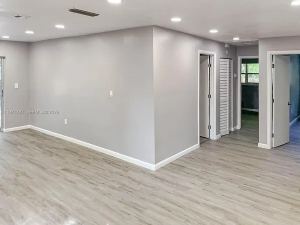 an empty room with wooden floor and entryway