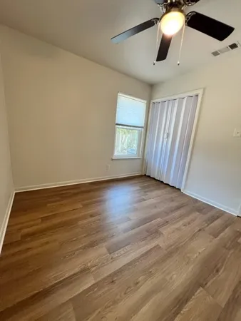 an empty room with wooden floor fan and windows