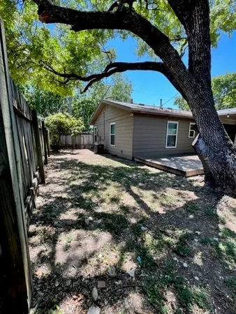 a backyard of a house with table and chairs under an umbrella