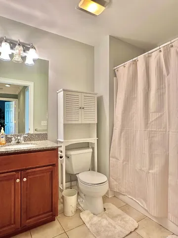 a bathroom with a granite countertop toilet sink and mirror