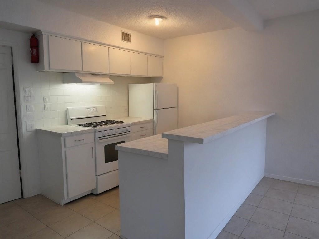 9745 Long Point Road, Unit 2 Houston, TX 77055 - Photo 5 of 7 a kitchen with white cabinets and white appliances