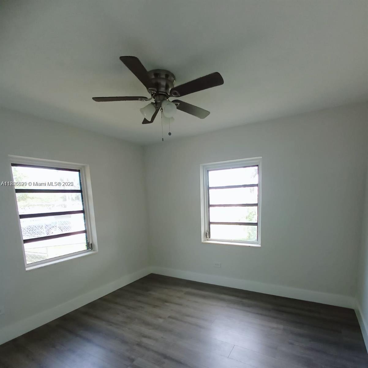 15061 Southwest 296th Street Homestead, FL 33033 - Photo 11 of 15 an empty room with wooden floor ceiling fan and windows