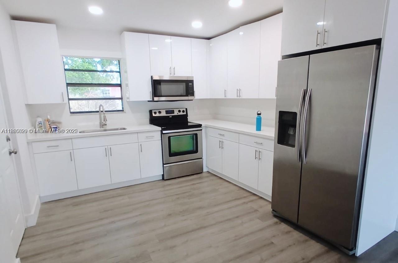 15061 Southwest 296th Street Homestead, FL 33033 - Photo 3 of 15 a kitchen with white cabinets and white appliances