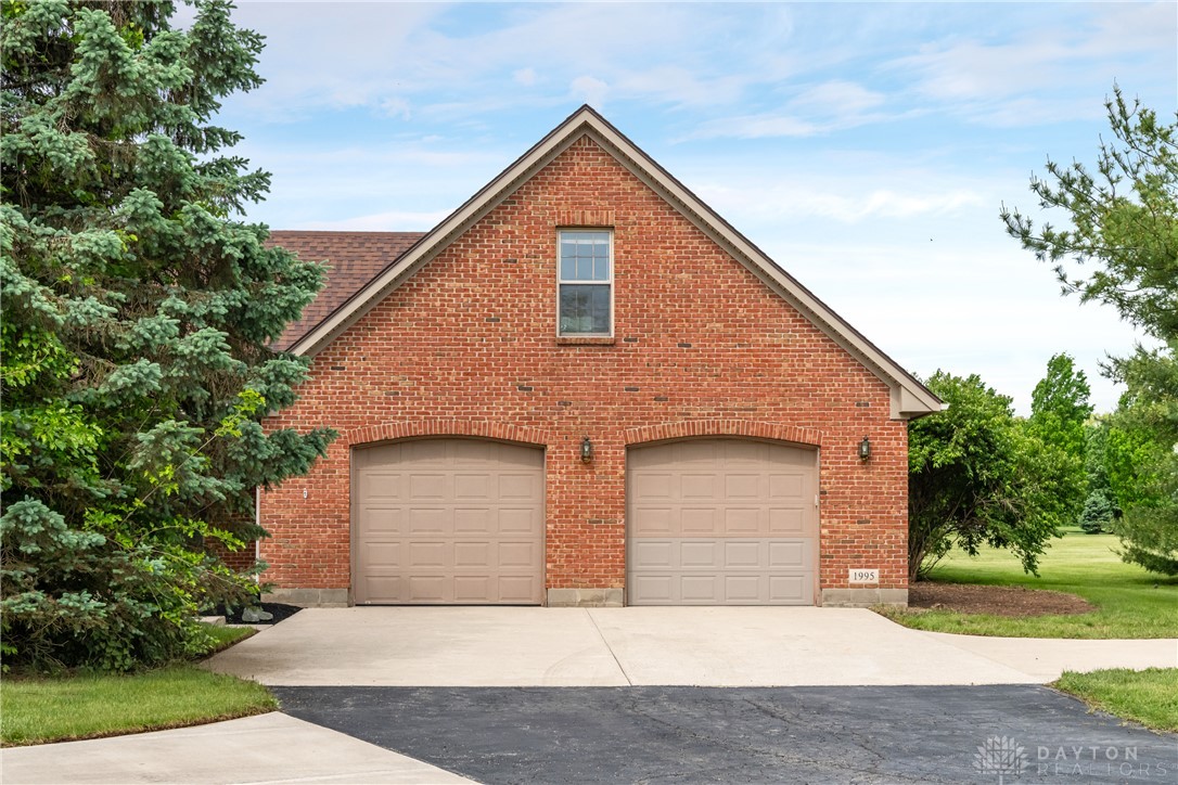9981 Ridge Acres Lane Englewood, OH 45322 - Photo 47 of 73 This brick structure features a two-car garage with arched entrances and a second-story window.