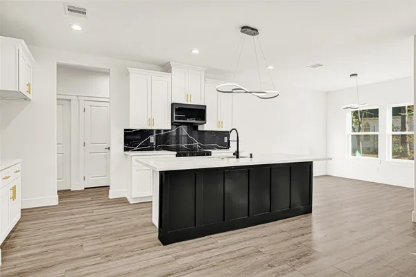 a large kitchen with stainless steel appliances granite countertop a lot of counter space and wooden floor