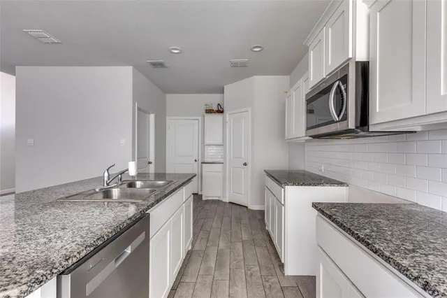 a kitchen with granite countertop cabinets stainless steel appliances and a counter space
