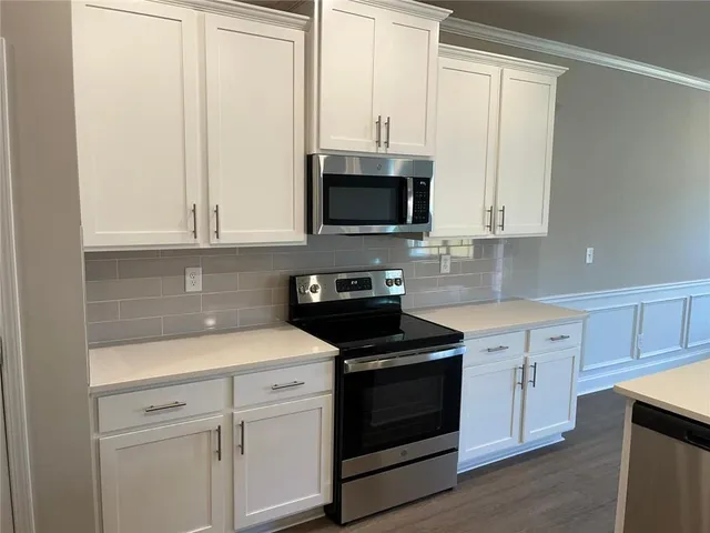 a kitchen with white cabinets and black appliances