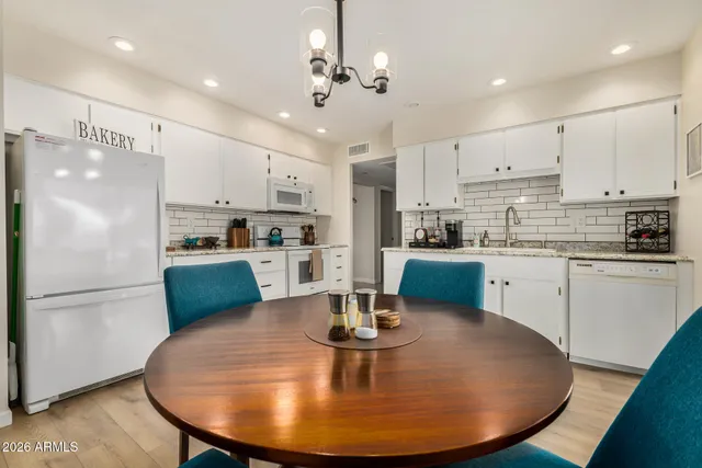 a kitchen with kitchen island a stove a refrigerator a sink a dining table and chairs with wooden floor