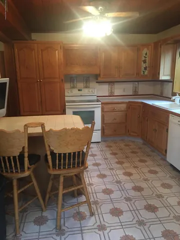 a kitchen with a dining table chairs and white appliances