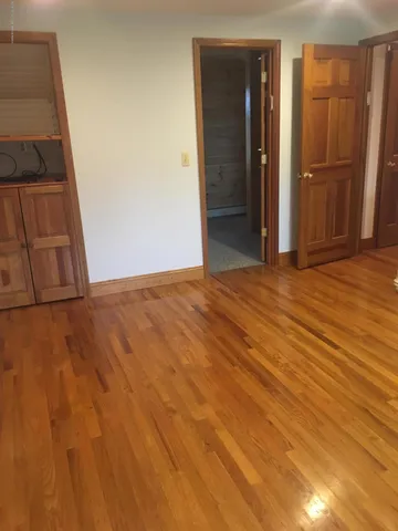 a view of an empty room with closet and wooden floor