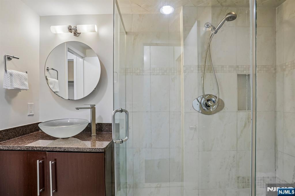 1077 River Road, Unit 1013 Edgewater, NJ 07020 - Photo 17 of 24 a bathroom with a granite countertop shower a mirror and a sink