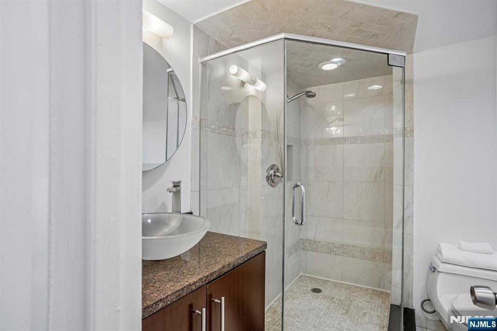 1077 River Road, Unit 1013 Edgewater, NJ 07020 - Photo 18 of 24 a bathroom with a granite countertop shower sink vanity and a mirror