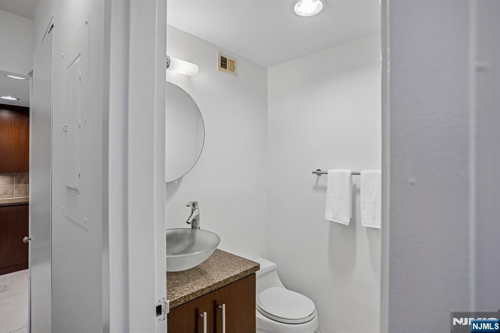 1077 River Road, Unit 1013 Edgewater, NJ 07020 - Photo 21 of 24 a bathroom with a granite countertop toilet and a sink