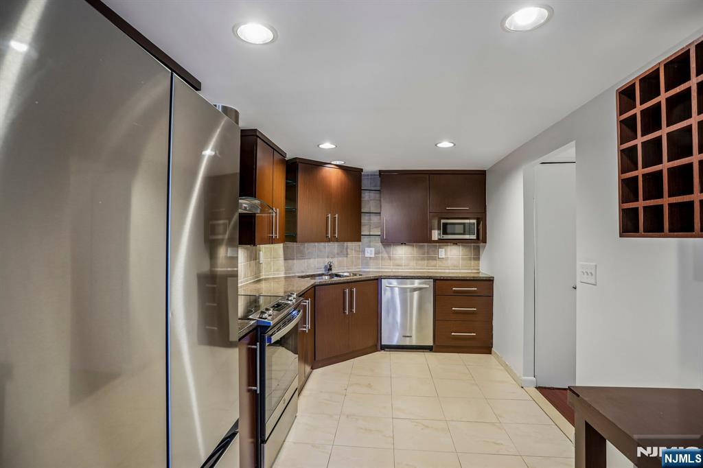 1077 River Road, Unit 1013 Edgewater, NJ 07020 - Photo 10 of 24 a large kitchen with stainless steel appliances kitchen island granite countertop a refrigerator and a sink