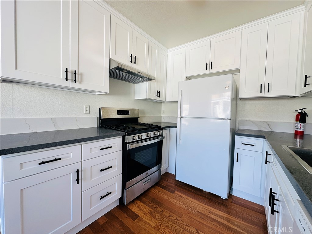 a kitchen with granite countertop white cabinets and stainless steel appliances