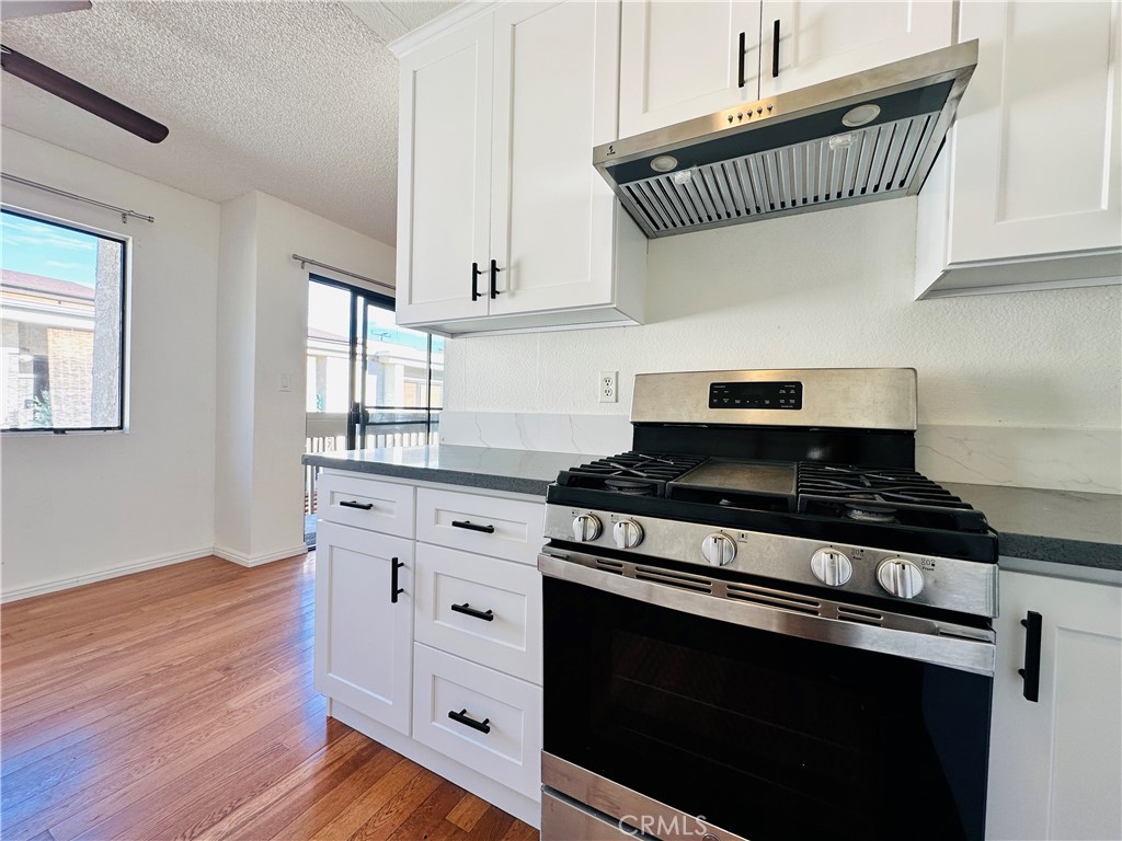 4146 Elm Avenue, Unit 5 Long Beach, CA 90807 - Photo 6 of 24 a kitchen with granite countertop a stove and a wooden floor