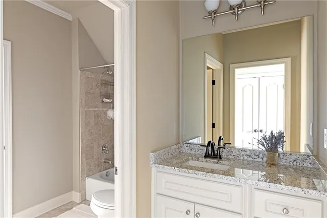 a bathroom with a granite countertop sink a toilet and shower