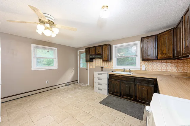 a kitchen with stainless steel appliances granite countertop a stove top oven a sink dishwasher a dining table and chairs with wooden floor