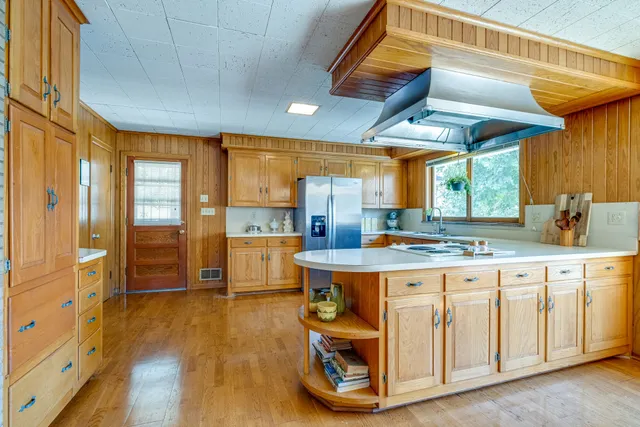 a kitchen with a stove and white cabinets with wooden floor