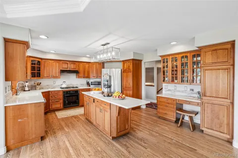 a large kitchen with stainless steel appliances a stove a sink dishwasher and a dining table with wooden floor