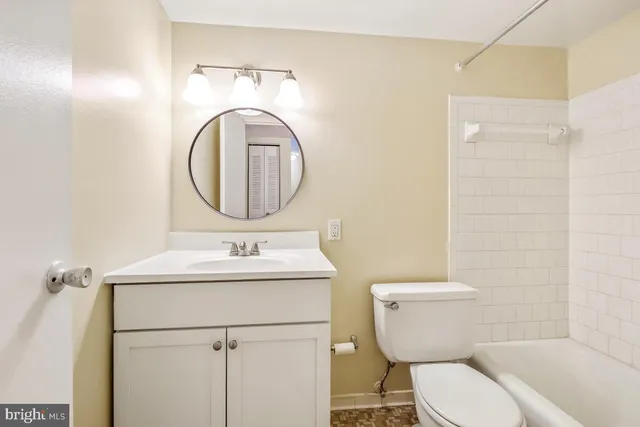 a view of a hallway with wooden floor and a bathroom