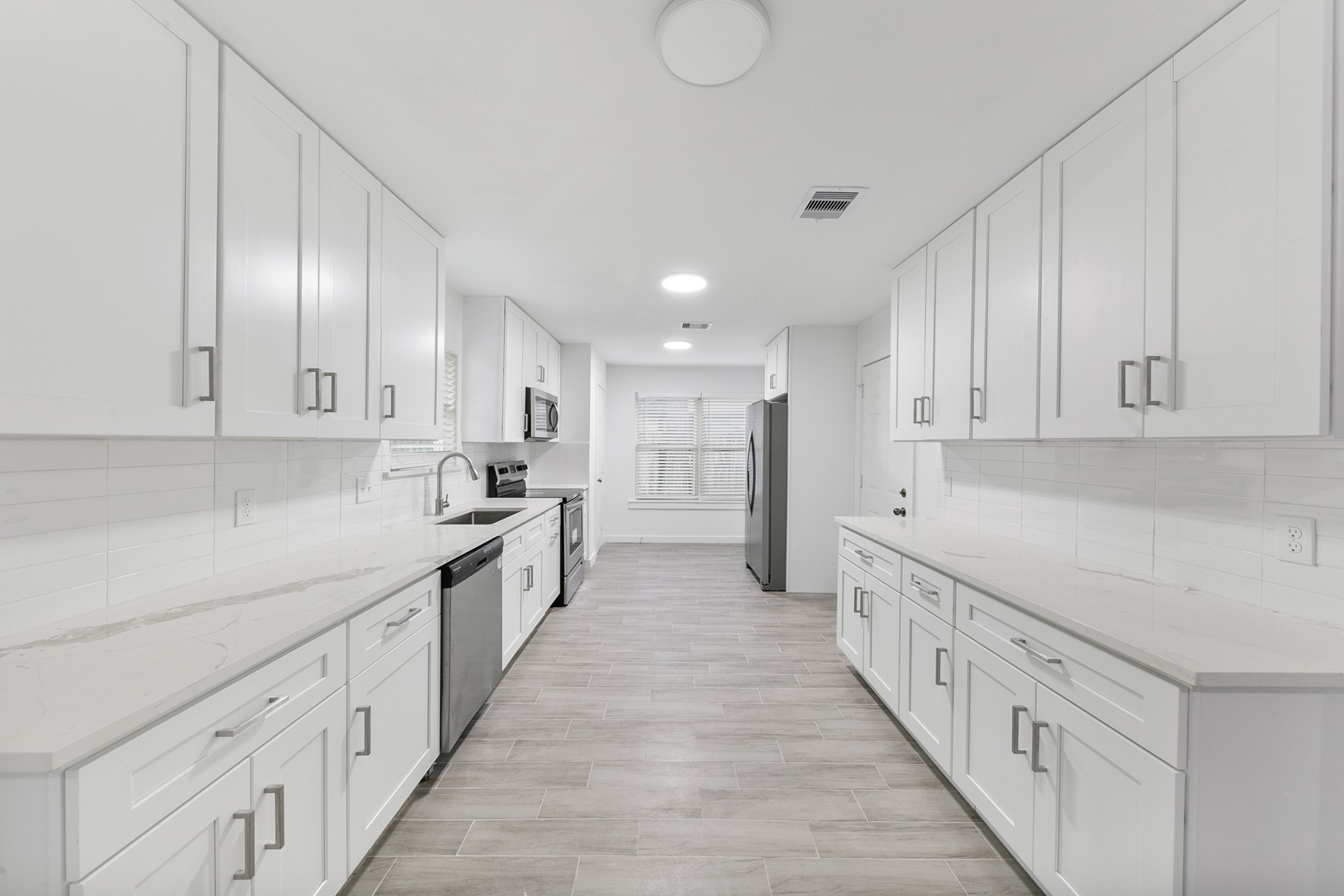 6811 McCullum Road Houston, TX 77489 - Photo 6 of 22 This spacious, modern kitchen features sleek white cabinetry, stainless steel appliances, and ample counter space, creating a bright and inviting atmosphere perfect for culinary enthusiasts.