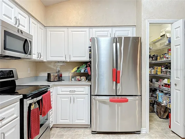 a kitchen with stainless steel appliances kitchen island granite countertop a refrigerator a stove a sink dishwasher and a dining table with wooden floor