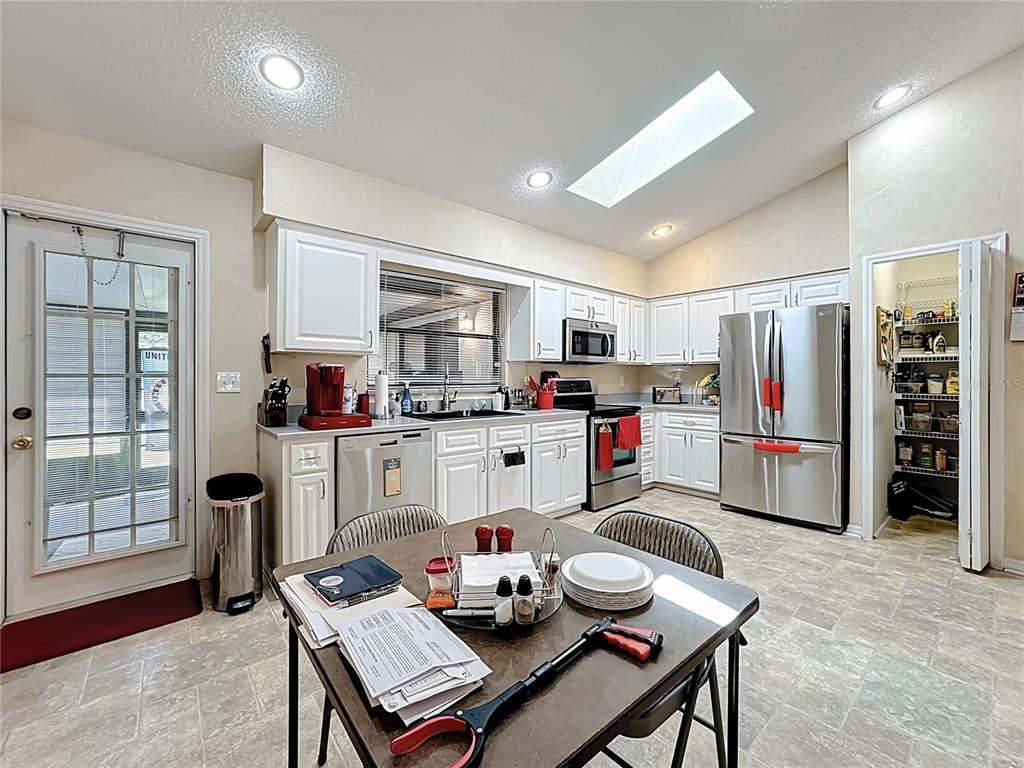 Undisclosed Address Winter Springs, FL 32708 - Photo 22 of 66 a kitchen with stainless steel appliances kitchen island granite countertop a refrigerator a stove a sink dishwasher and a dining table with wooden floor