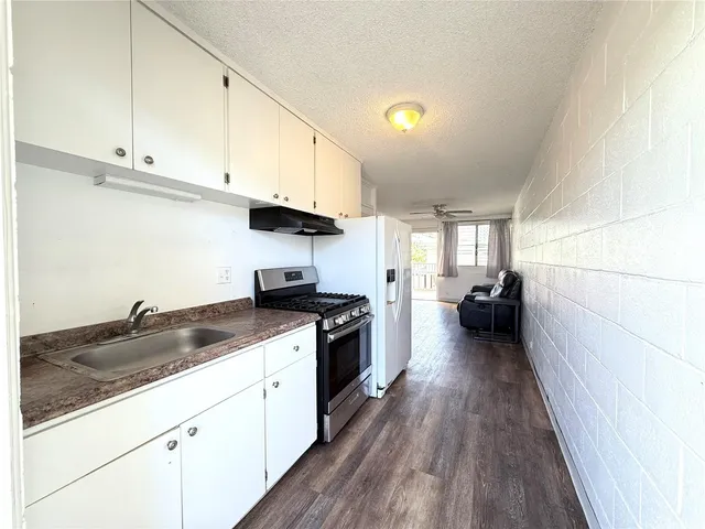 a kitchen with granite countertop a sink a stove top oven and cabinetry