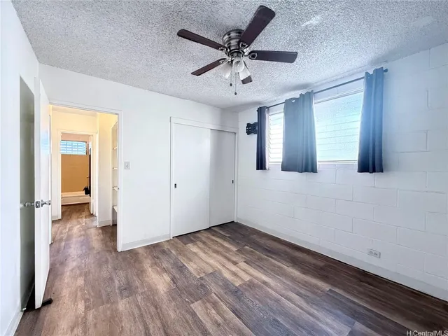 an empty room with wooden floor and a ceiling fan