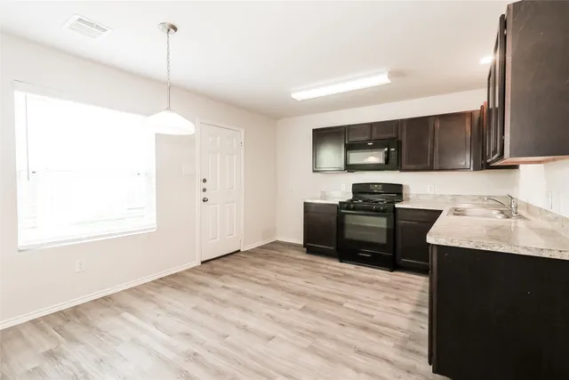 a kitchen with granite countertop a stove a sink and a wooden floor